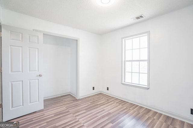 unfurnished bedroom with a textured ceiling and light hardwood / wood-style floors