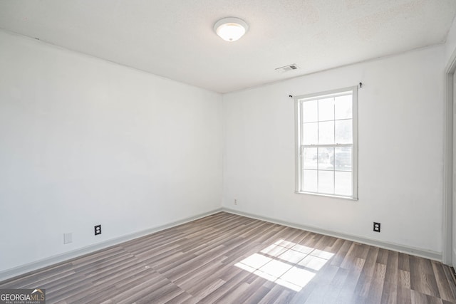 unfurnished room featuring wood-type flooring and a textured ceiling