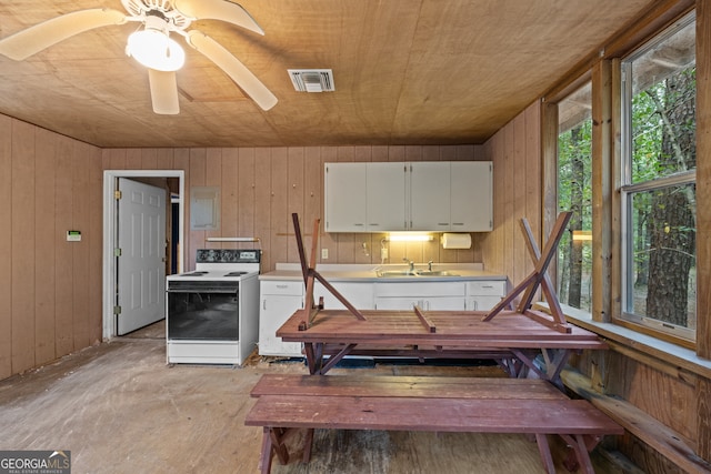 kitchen featuring sink, white cabinetry, wood walls, white range with electric stovetop, and ceiling fan