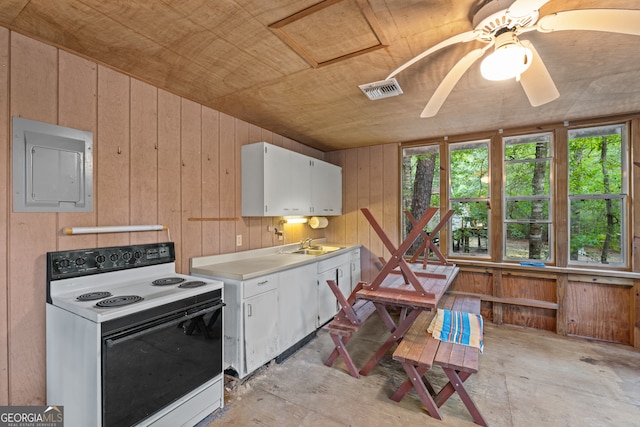 kitchen featuring ceiling fan, white cabinets, sink, wooden walls, and white range with electric cooktop