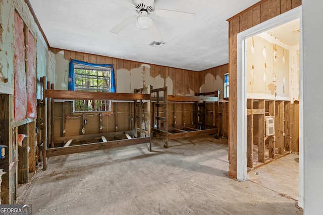 miscellaneous room featuring ceiling fan and wooden walls