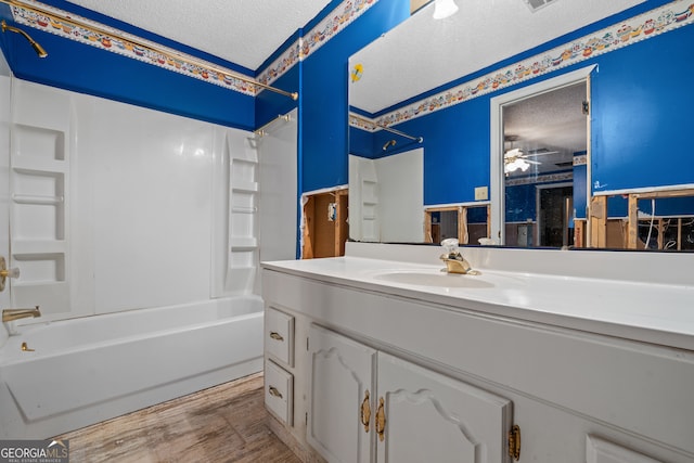 bathroom featuring  shower combination, ceiling fan, vanity, and a textured ceiling