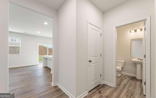 corridor with a sink, recessed lighting, wood finished floors, and baseboards