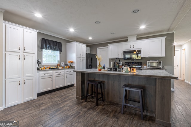 kitchen with white cabinets, black appliances, and a kitchen island with sink