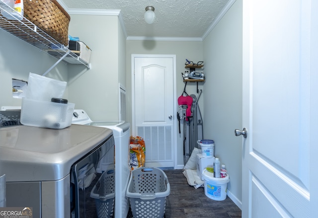 clothes washing area with a textured ceiling, ornamental molding, dark hardwood / wood-style flooring, and washer and dryer