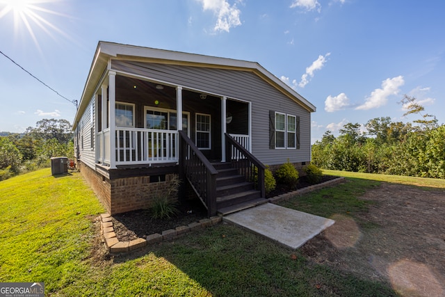 view of front of property featuring covered porch, central AC unit, and a front yard