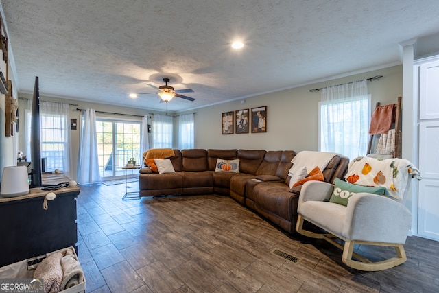 living room with ceiling fan, a textured ceiling, dark hardwood / wood-style floors, and ornamental molding