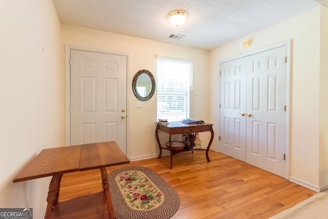 foyer entrance featuring a textured ceiling and light hardwood / wood-style flooring