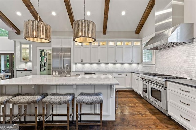 kitchen featuring wall chimney exhaust hood, backsplash, premium appliances, and a kitchen island with sink