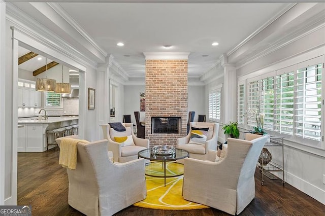 living room with crown molding, sink, dark wood-type flooring, and a brick fireplace