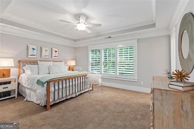 carpeted bedroom with ceiling fan, a raised ceiling, and crown molding