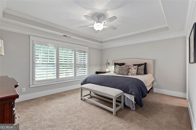 bedroom featuring carpet floors, a tray ceiling, ornamental molding, and ceiling fan