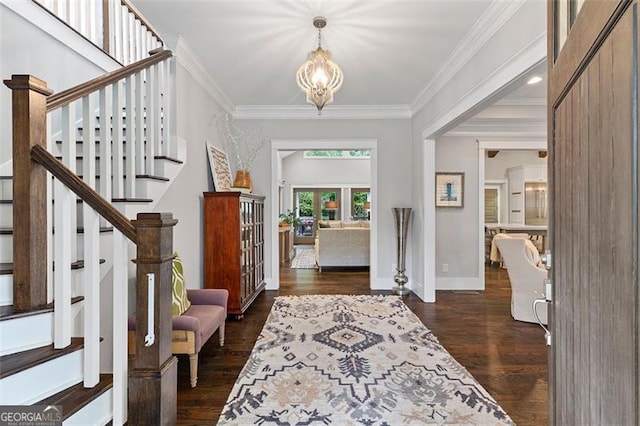 foyer entrance featuring dark hardwood / wood-style floors, ornamental molding, and a chandelier