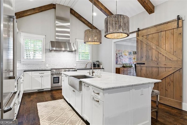 kitchen with pendant lighting, an island with sink, sink, and a barn door