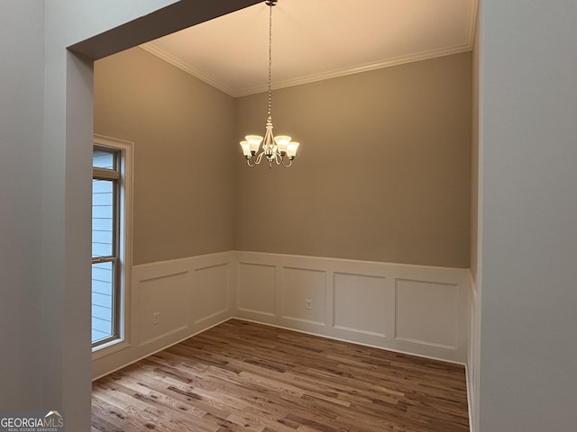 5544 Whispering Swan Ct, Douglasville, GA 30135 - empty room featuring crown molding, wood finished floors, a chandelier, wainscoting, and a decorative wall
