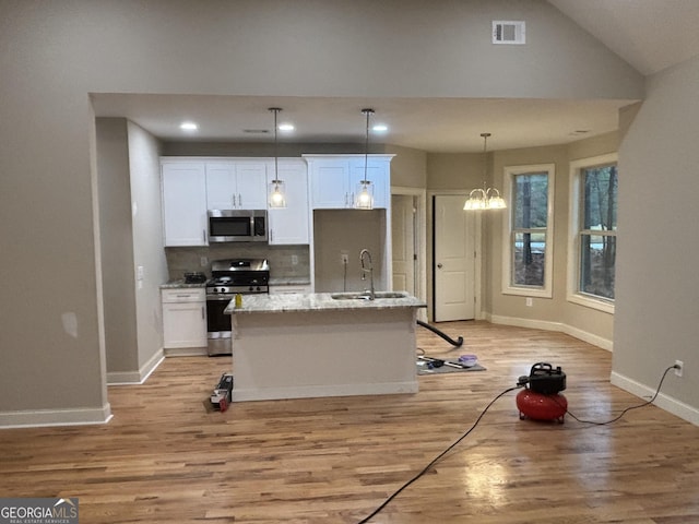 kitchen featuring white cabinetry, a kitchen island with sink, stainless steel appliances, and a notable chandelier