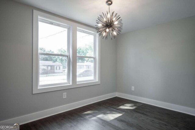 empty room featuring a chandelier and dark hardwood / wood-style floors