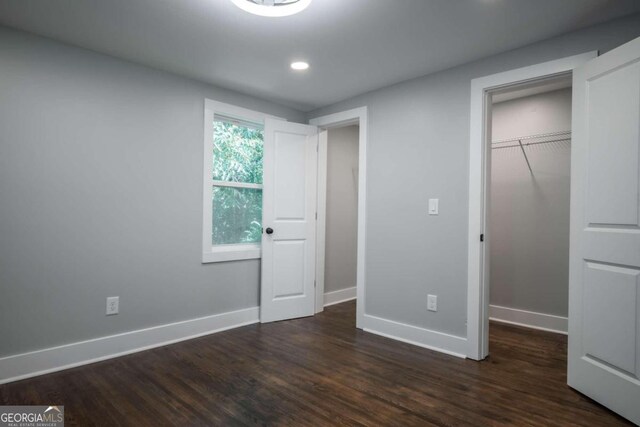 unfurnished bedroom featuring dark wood-type flooring and a closet