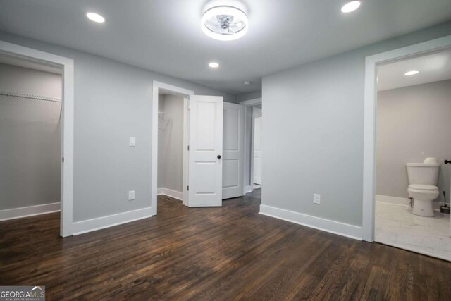 unfurnished bedroom featuring dark hardwood / wood-style floors and connected bathroom