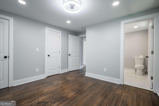 unfurnished bedroom with ensuite bathroom and dark hardwood / wood-style floors