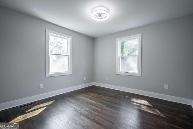 spare room with a wealth of natural light and dark hardwood / wood-style flooring