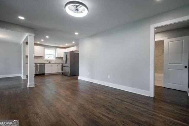 unfurnished living room featuring sink and dark hardwood / wood-style flooring