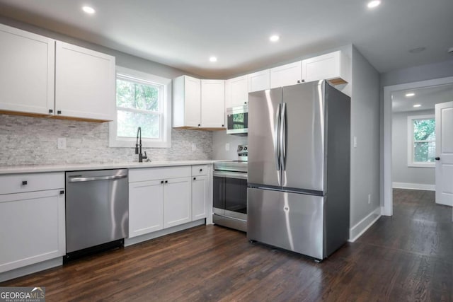 kitchen with dark hardwood / wood-style flooring, tasteful backsplash, appliances with stainless steel finishes, and white cabinets