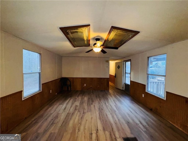 spare room featuring ceiling fan, hardwood / wood-style floors, and wood walls