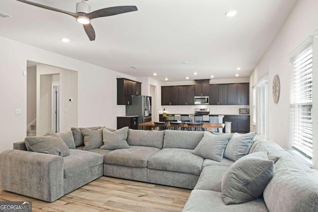 living room featuring light wood-type flooring and ceiling fan