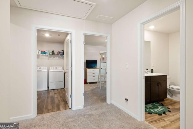 corridor featuring washing machine and dryer, sink, and light carpet