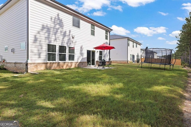 back of property featuring a patio, a trampoline, and a yard