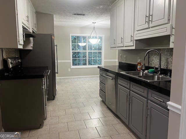 kitchen with white cabinets, sink, a textured ceiling, stainless steel appliances, and decorative backsplash