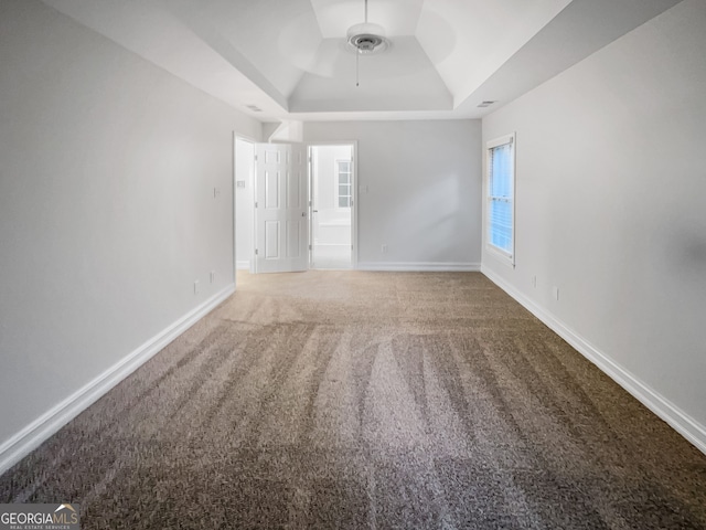 unfurnished bedroom featuring ceiling fan, a raised ceiling, and carpet flooring