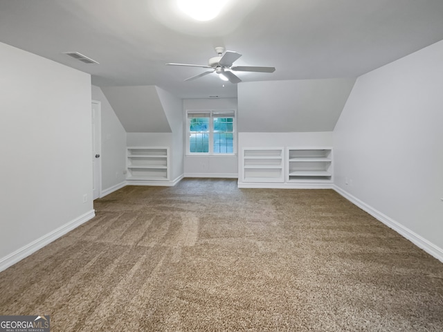 additional living space featuring built in shelves, lofted ceiling, ceiling fan, and carpet flooring