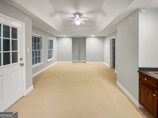 carpeted spare room with ceiling fan and a raised ceiling