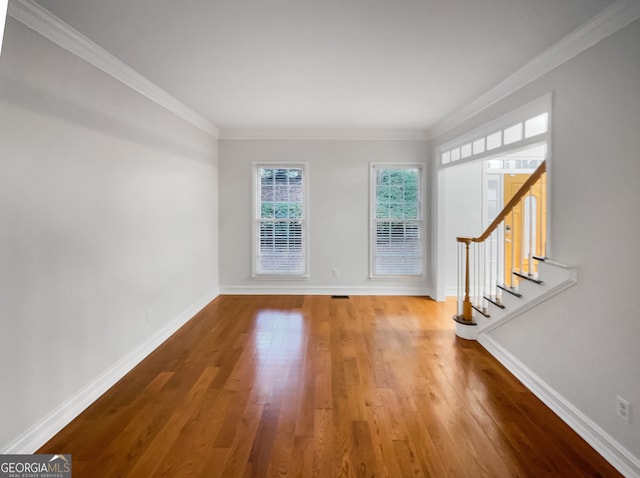 empty room with hardwood / wood-style flooring and crown molding