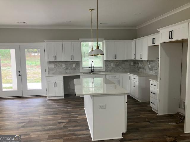 kitchen with white cabinetry, hanging light fixtures, a center island, dishwasher, and dark hardwood / wood-style flooring