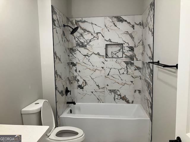 full bathroom featuring vanity, tiled shower / bath combo, and toilet