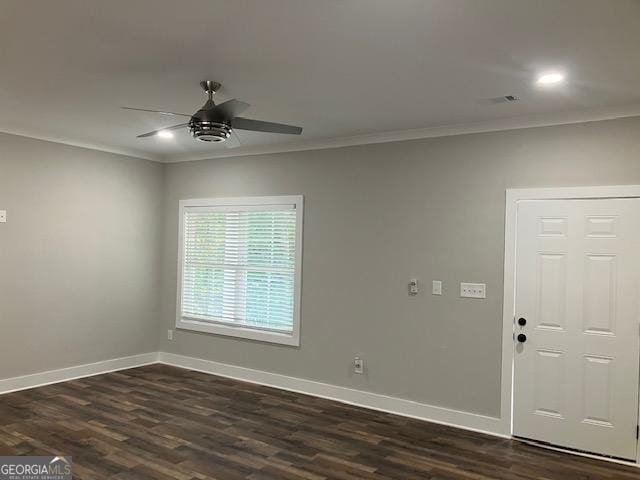 spare room featuring dark wood-type flooring, ceiling fan, and crown molding