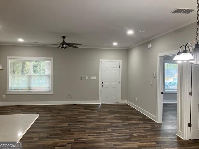 interior space featuring ornamental molding, ceiling fan with notable chandelier, and dark wood-type flooring