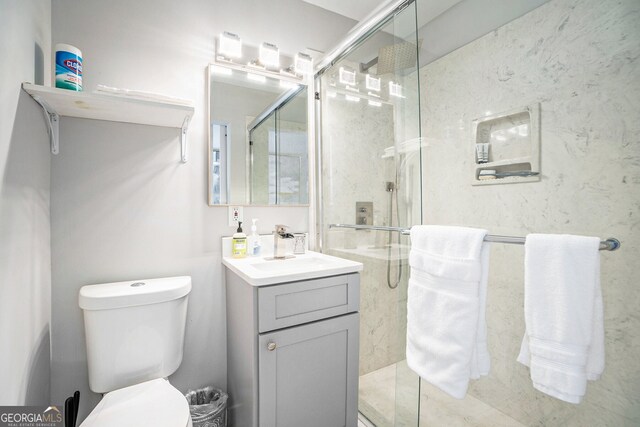 bathroom featuring vanity, toilet, and a shower with door