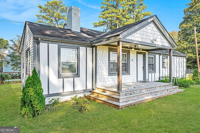 back of house featuring a lawn and covered porch