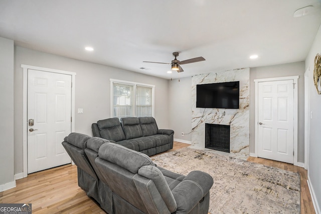 living room with ceiling fan, a fireplace, and light hardwood / wood-style floors