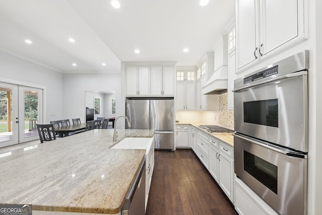 kitchen with stainless steel appliances, white cabinetry, a spacious island, and dark hardwood / wood-style flooring