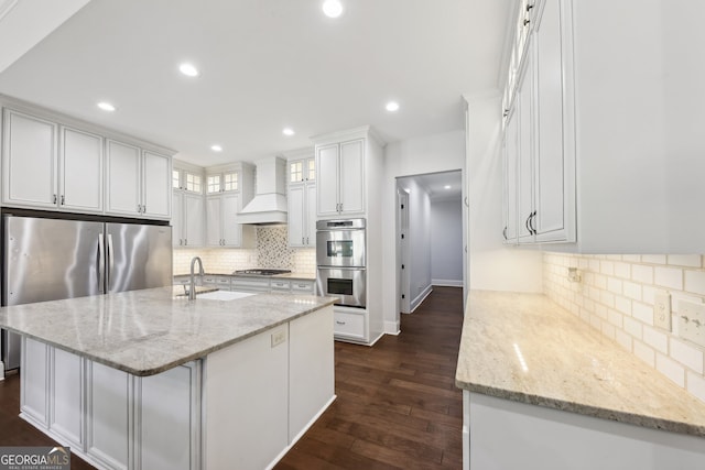 kitchen featuring stainless steel appliances, white cabinetry, light stone counters, custom exhaust hood, and dark wood-type flooring