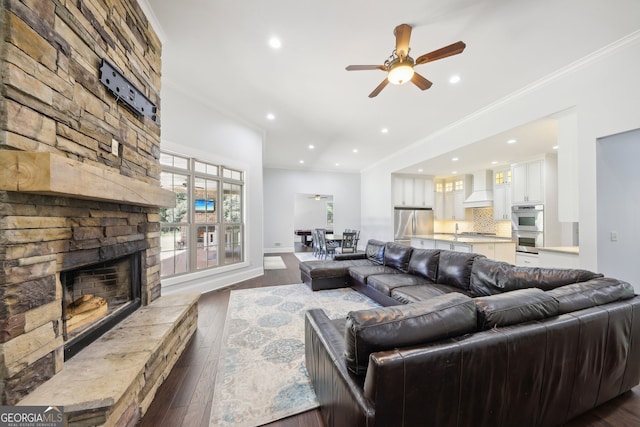 living room with ceiling fan, hardwood / wood-style flooring, ornamental molding, and a fireplace