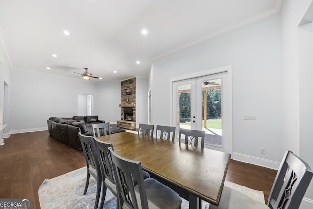 dining room featuring french doors, crown molding, a stone fireplace, dark hardwood / wood-style flooring, and ceiling fan