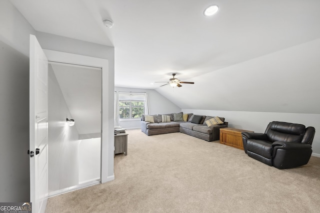 carpeted living room with ceiling fan and vaulted ceiling