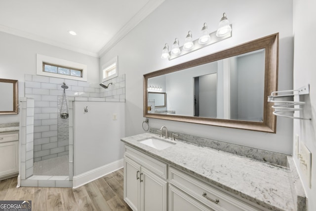 bathroom featuring wood-type flooring, vanity, tiled shower, and ornamental molding