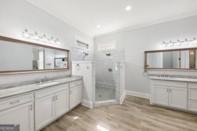 bathroom featuring ornamental molding, vanity, wood-type flooring, and tiled shower